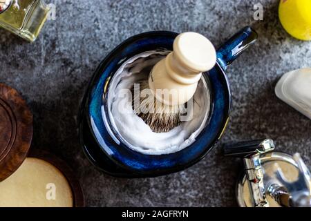 High-Angle Schuss Rasiercreme und Bürste auf ein Graue Oberfläche Stockfoto