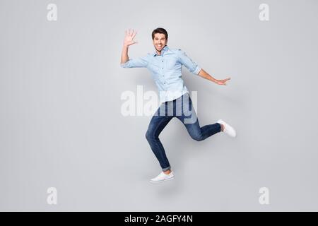 Volle Länge Körper größe Profil Seite Foto von fröhlichen aufgeregt, netter Kerl trägt Schuhe, die für die Verkäufe auf Zeit über Grau isoliert Stockfoto