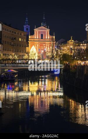 Ljubljana, Slowenien - 18 Dezember, 2019: Blick auf den Fluss Ljubljanica Tromostovje, und Franziskaner Kirche der Verkündigung im alten Stadtzentrum eingerichtet wit Stockfoto