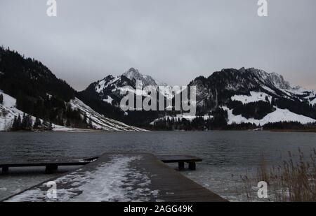 Dunkelgrau Stimmung über Winter Mountain Lake Schwarzsee im Kanton Freiburg, Schweiz Stockfoto