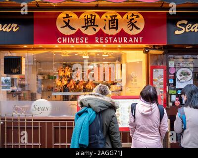 Leute, die in das Fenster eines chinesischen Restaurant in Gerard Street London UK in London Chinatown Stockfoto