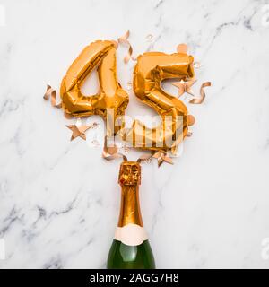 Champagner Flasche mit gold Nummer 45 Ballon. Minimal party Jubiläum Konzept Stockfoto