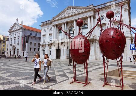 Lissabon, Portugal: Zwei junge Frauen vorbei an ein modernes Bügeleisen Statue neben der neoklassizistischen Rathaus (Paços do Concelho) auf dem Platz der Stadt (Praç entfernt Stockfoto