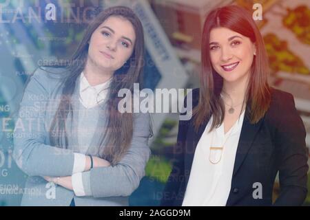 Zwei junge erfolgreiche Unternehmerinnen stehen in der Halle und auf der Suche nach der Kamera, zwei geschäftsfrauen posieren für werbliche Inhalte, während standin Stockfoto