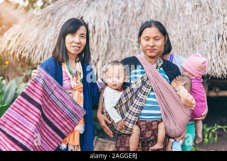 LAMPHUN THAILAND - 8. Dezember: Nicht identifizierte weibliche Touristen ein Bild mit Karen Familie auf Dezember 8,2019 bei Karen Dorf in Lamphun, Thailand Stockfoto