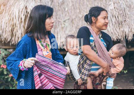 LAMPHUN THAILAND - 8. Dezember: Nicht identifizierte weibliche Touristen ein Bild mit Karen Familie auf Dezember 8,2019 bei Karen Dorf in Lamphun, Thailand Stockfoto