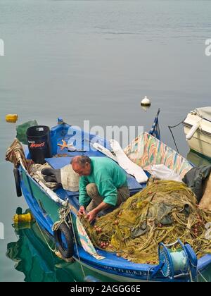 Kavala, Mazedonien/Griechenland - 14. Mai 2019: Fischer auf seinem fischernetze in traditionellen verwittertem Blau Holz- Boot im Hafen von Kavala. Stockfoto