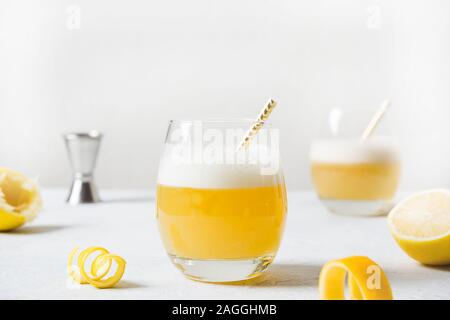 Whiskey Sour Cocktails mit Zutaten, Zitronensaft, Zuckersirup und Eiweiß in Glas auf weißer Tisch. Horizontale Ausrichtung. Hausgemachte trinken. Stockfoto