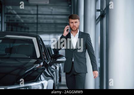 In Gespräch. Modernes, stilvolles bärtigen Geschäftsmann im Automobil Salon Stockfoto