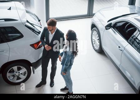 Mädchen in legere Kleidung. Weibliche Kunden und modernen stilvollen bärtigen Geschäftsmann im Automobil Salon Stockfoto
