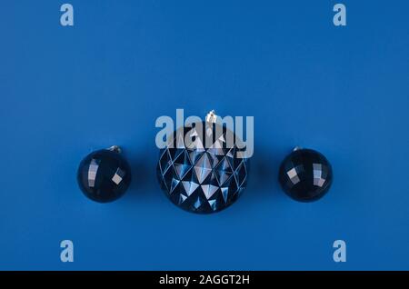 Weihnachten oder Neujahr Hintergrund. Drei blaue dekorative Kugeln auf dunkelblauen Hintergrund. Weihnachten Konzept. Flach, Ansicht von oben, kopieren. Temp. Stockfoto