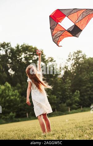 Ich glaube, dass ich fliegen kann. Glückliches Mädchen in weißen Kleidern viel Spaß mit Kite im Feld. Schöne Natur Stockfoto