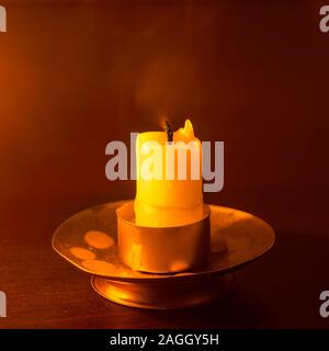 Erloschene Kerze auf einem Holztisch in der Nacht Stockfoto
