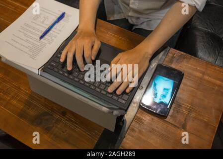 Hohe Betrachtungswinkel von menschlichen Händen Laptop Tastatur eingeben Stockfoto