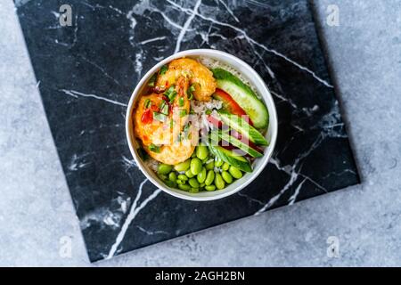 Nehmen Sie gesund Buddha Schüssel mit Garnelen, Edamame Bohnen, Gurken und Basmatireis/Poke Schüssel in Kunststoffbox Paket oder Container. Traditionelle Speisen. Stockfoto