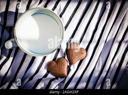 Herzförmige Kekse und Milch in eine Schüssel geben. Stockfoto