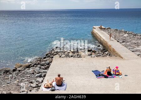 Menschen beim Sonnenbaden auf konkretes Deck am Strand, Madeira, Portugal Stockfoto