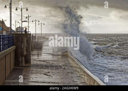 Im Bild: Ein einsamer Mann steht die Wellen gegen die Promenade Wand in Porthcawl, Wales, Großbritannien zu beobachten. Dienstag, 01 Oktober 2019 Re: Schwere Regen- und st Stockfoto