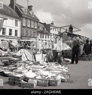 1960er Jahre, historischer Freiluft-Marktstand, auf dem Markthügel in St Ives, Cambridgeshire, England, Großbritannien, mit der Statue von Oliver Cromwell auf der rechten Seite. Stockfoto