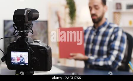 Kreative junge Menschen die Aufnahme einer Buchbesprechung für seine soziale Medien. Berühmte Beeinflusser. Stockfoto