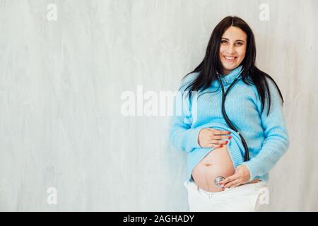 Schwangere Mama hört ein Stethoskop Magen Stockfoto