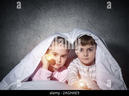 Kinder mit Taschenlampen im Bett Stockfoto