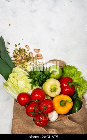 Umweltfreundliche Stofftasche voller frischem Gemüse auf einem hellen Hintergrund. Ansicht von oben. Null Abfall Käufe Konzept. Gesunde, ausgewogene Ernährung. Stockfoto