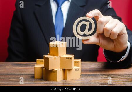 Unternehmer hält eine e-mail Internet Symbol über Boxen. Verkauf und Vertrieb von Waren und Produkten durch online. Werbung und Marketing, Verkauf. S Stockfoto