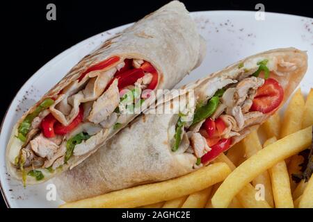 Alternative Taco oder Burrito mit traditionellen sandwich Füllungen in einer Tortilla gewickelt. Cheesy chicken Wrap in Tortilla auf weiße Platte serviert. Stockfoto