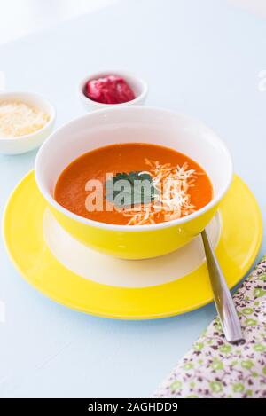 Karotte Käse Suppe mit Petersilie in gelb Schüssel, blauen Hintergrund. Gesunde Ernährung Konzept. Stockfoto