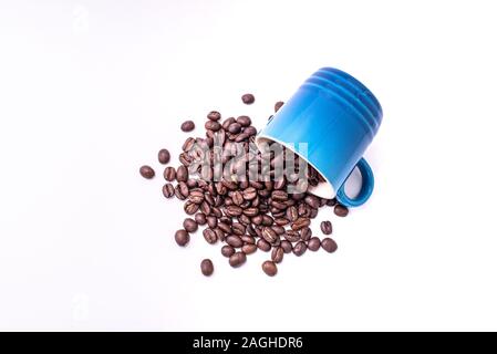 Verschüttete Kaffeebohnen aus einem Becher über einem weißen Hintergrund isoliert Stockfoto