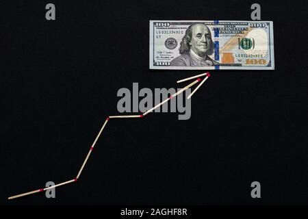 Die weißen Streichholz Pfeil zeigt den Dollar auf einem schwarzen Hintergrund steigt. Stockfoto