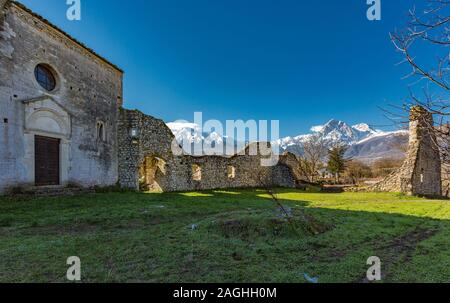 Ruinen der Abtei von San Giovanni Ad Insulam, Isola del Gran Sasso. Im Hintergrund die schneebedeckten Gran Sasso Kette Stockfoto