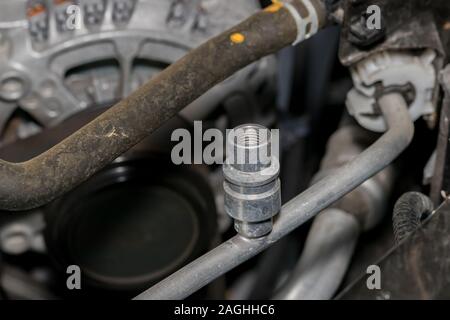 Nahaufnahme des Automotive Air Conditioner Hochdruckseite service port für freon Kältemittel unter der Motorhaube des Autos. Konzept der Auto Wartung und Reparatur Stockfoto