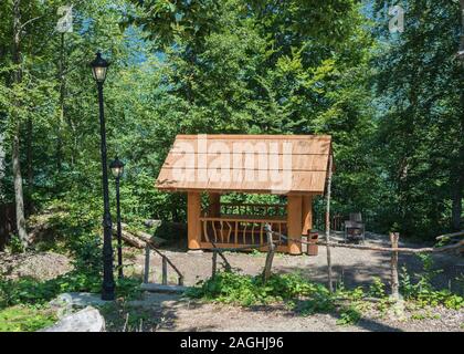 Schönen Sommer housefrom ein Protokoll von einem großen Baum mit Barbecue zum Grillen im Wald Stockfoto