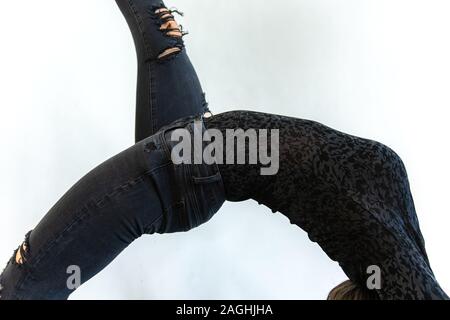 Eine Nahaufnahme und Side Shot auf Die gekrümmte Wirbelsäule und Körper einer Frau mit schwarzen floral bedrucktes Shirt und dunkle Jeans Stockfoto