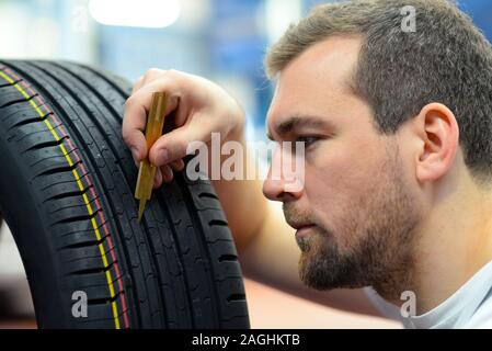 Mechaniker steuert die Profiltiefe der Reifen Stockfoto