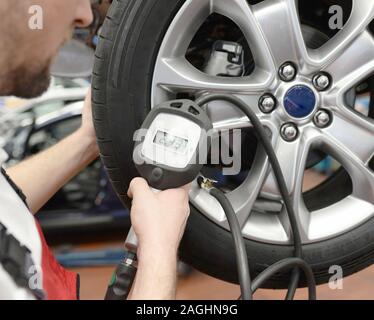 Automechaniker prüft den Luftdruck eines Reifens in der Garage Stockfoto