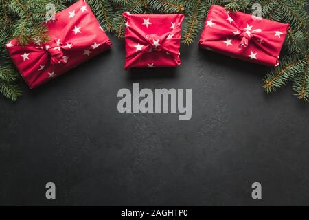 Weihnachten Rahmen mit Geschenken Rot Textil, tannenzweigen auf schwarz gehüllt. Merry Xmas card. Winter Urlaub. Frohes neues Jahr. Platz für Text. Blick von abov Stockfoto