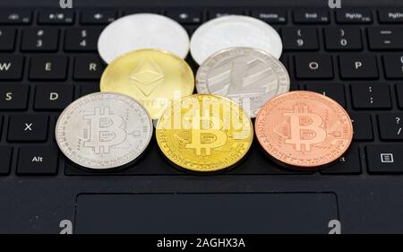 Cryptocurrency Münzen Bitcoin, Litecoin, des Astraleums und Welligkeit, auf einem Schwarz Computer Tastatur platziert. Stockfoto