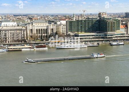 BUDAPEST, Ungarn - März 2018: Lange Lastkahn durch das Zentrum von Budapest vorbei, wie es fließt die Donau. Auf der Rückseite sind zwei Autos Stockfoto