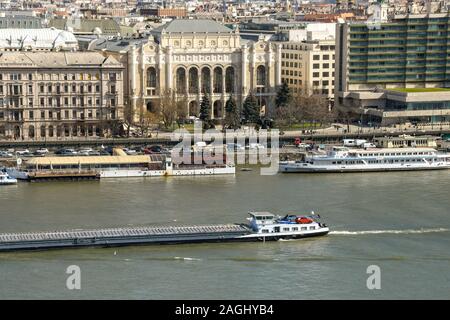 BUDAPEST, Ungarn - März 2018: Lange Lastkahn durch das Zentrum von Budapest vorbei, wie es fließt die Donau. Auf der Rückseite sind zwei Autos Stockfoto