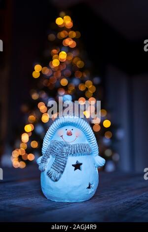 Wenig dekorativen Schneemann Spielzeug auf dem Tisch über leuchtenden Weihnachtsbaum Hintergrund , Winterurlaub, traditionellen Symbol Stockfoto