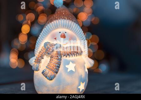 Wenig dekorativen Schneemann Spielzeug auf dem Tisch über leuchtenden Weihnachtsbaum Hintergrund , Winterurlaub, traditionellen Symbol Stockfoto