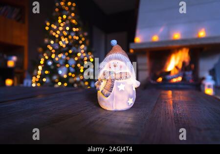 Stilvolle Weihnachtsdekoration, nette kleine keramische Schneemann Souvenir mit Kerze drin, neues Jahr Urlaub in der gemütlichen Haus mit Kamin und Dekor Stockfoto