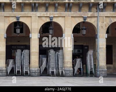 Chromrahmen, restaurant Stühle in einem öffentlichen Platz mit nummerierten Balkone in San Sebastian, Spanien, Europa gestapelt Stockfoto