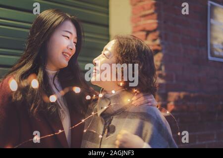 Gerne asiatische ältere Mutter und erwachsene Tochter an einander an der Portland Pearl District Nacht suchen Stockfoto