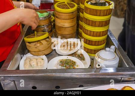 Chinesische Kellnerin catering dimsum in Bambus steamer, in Restaurant Stockfoto