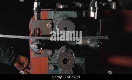Schmiedewerkstatt auf dem Tisch. Arbeitnehmer Biegungen die Metallstange auf das schmiedeeiserne runde Biegemaschine. Herstellung von einem Designer Teil aus einer Metallstange. Stockfoto