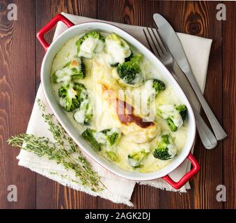 Hähnchenbrustfilet überbacken mit Broccoli in bechamelsauce Soße auf einem dunklen Holztisch. Gesunde Nahrung, sauberes Essen, Ansicht von oben. Stockfoto